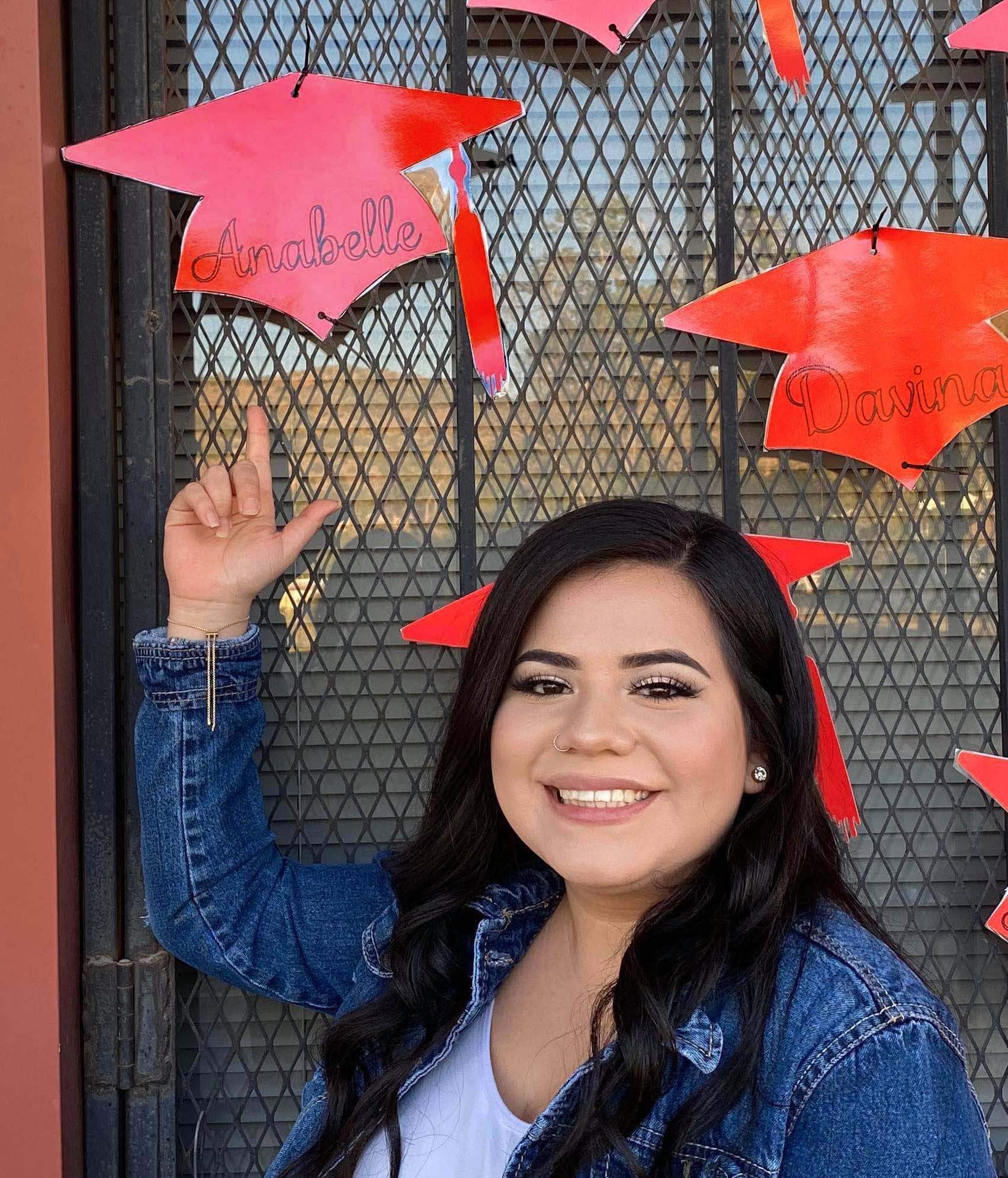 Annabelle in front of her personalized graduation cap decoration by Anna Villalobos