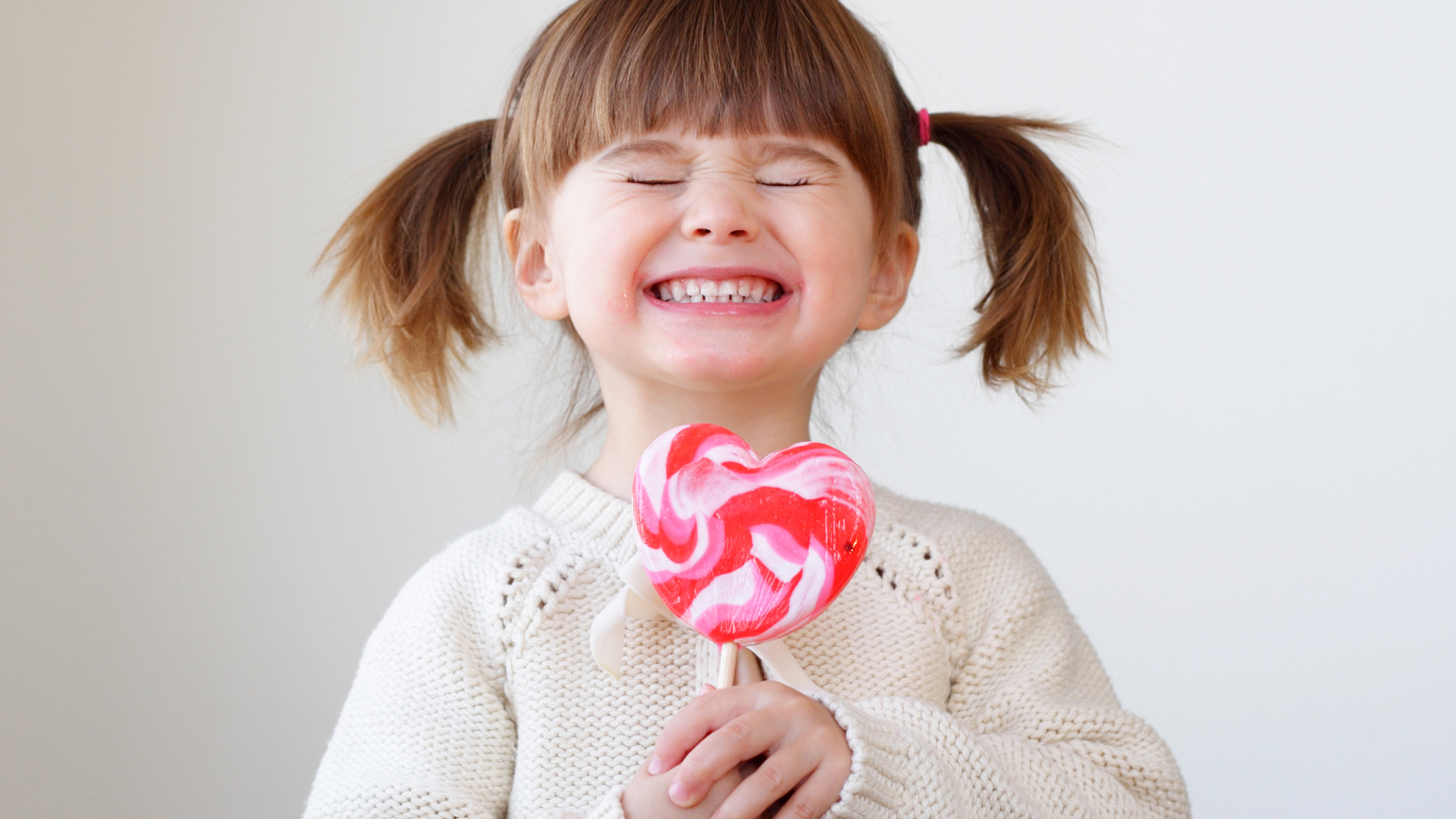 child holding heart shaped lollipop