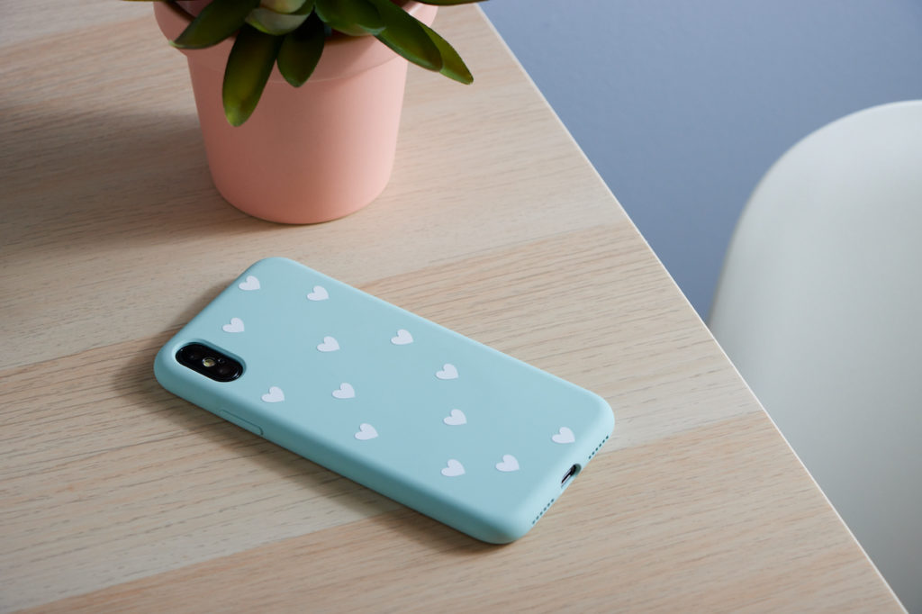 Blue phone case with white vinyl hearts on desk