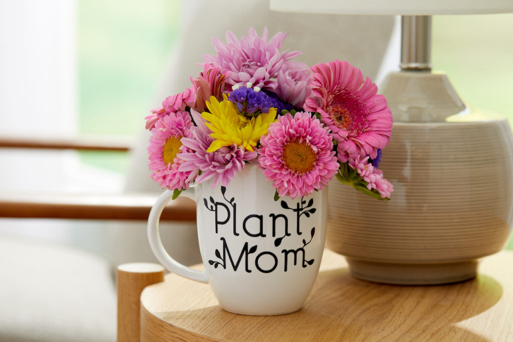 "Plant mom" mug holding bouquet of flowers