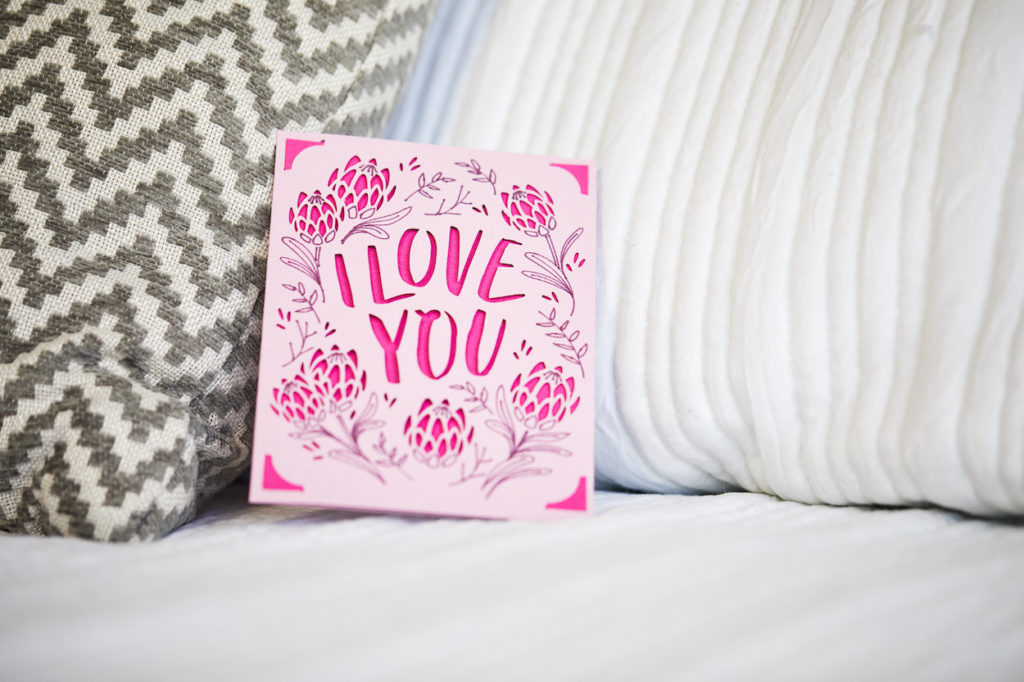 "I love you" pink greeting card on bed