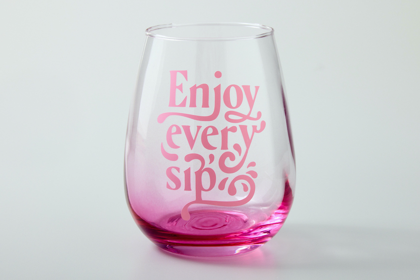 A photo of a pink wine glass that read, "enjoy every sip."