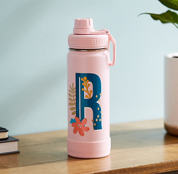 A pink water bottle with a blue, floral monogram of the letter "R" on it.
