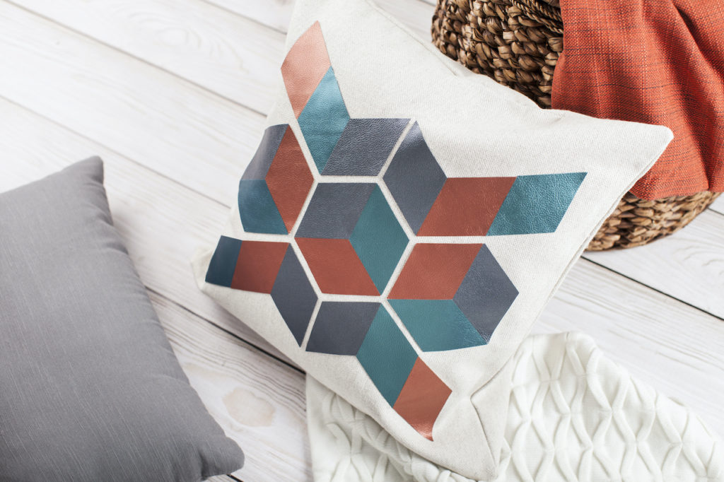 A pillow with a printed geometric pattern, surrounded by other cozy elements like pillows and blankets.