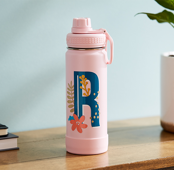 A Custom and unique pink water bottle with a blue, floral monogram of the letter "R" on it. 