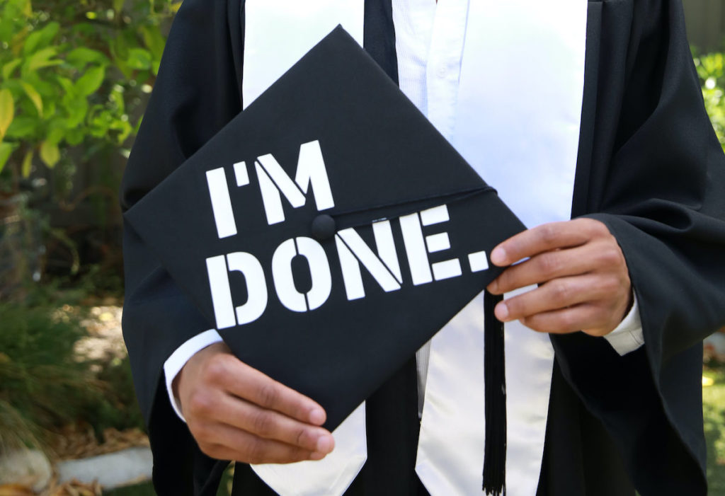 Graduation cap design reading "I'm Done" being held by a student.