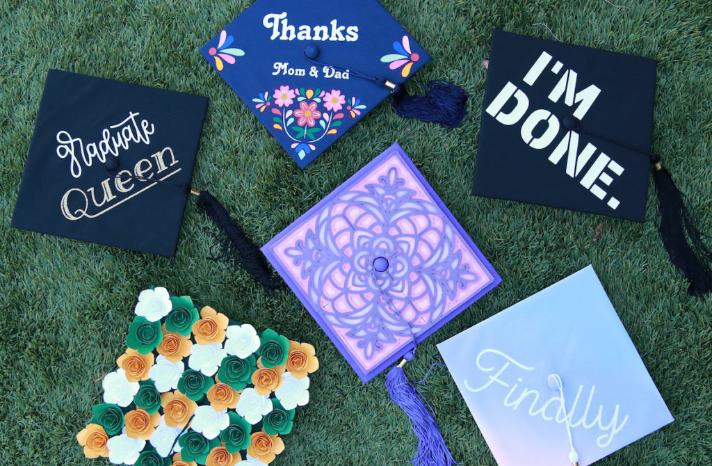 Graduation cap designs sitting on green grass.