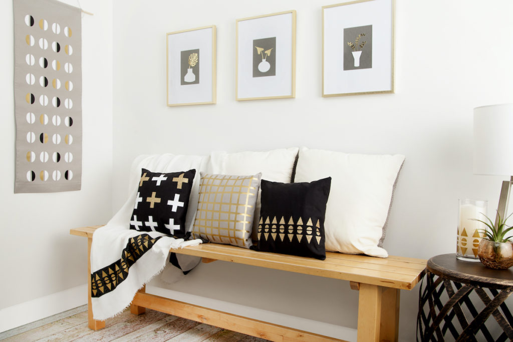 Neutral colored pillows sit on a wooden bench in an entryway of a home. 