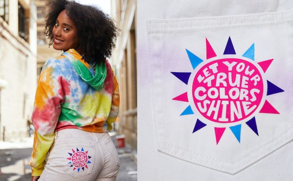 The first Pride outfit idea features a pink, blue, and purple sunburst patch that is ironed onto a white denim shorts pocket. 