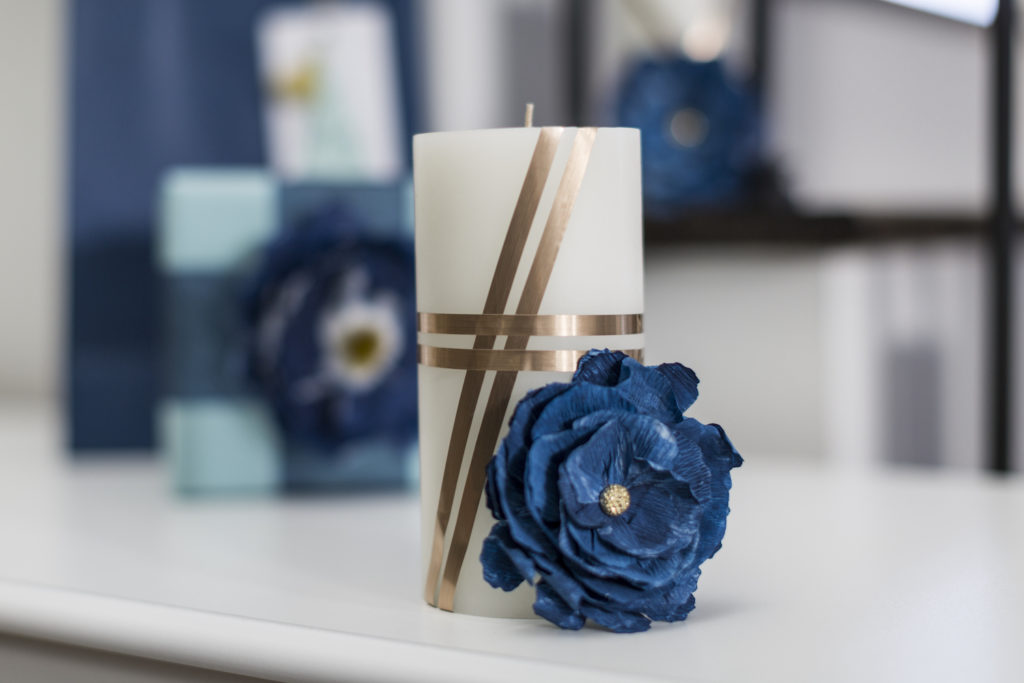 Another cheap way to turn your bathroom into a spa, A gold accented candle with blue flower decoration.