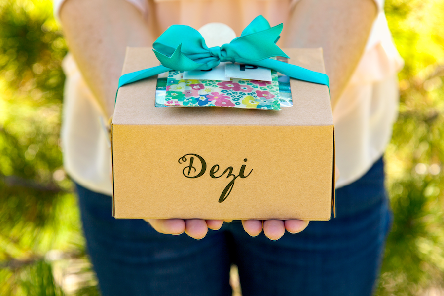 A woman holds out a customized cardboard picnic box with a blue bow on it