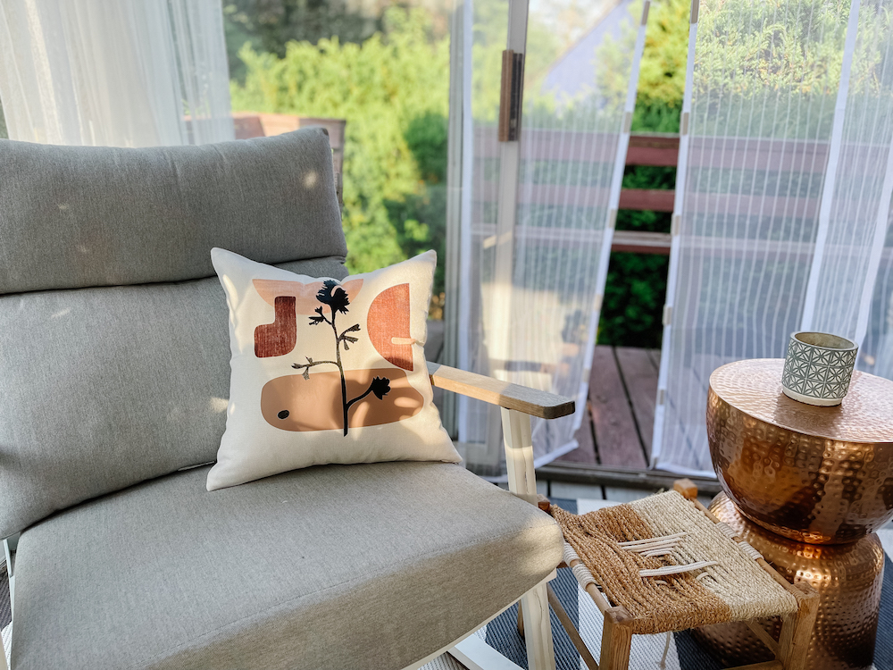 A contemporary, organic modern pillow created with Cricut sits on a grey outdoor chair

