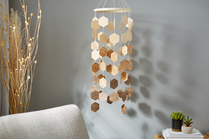 A wooden hanging mobile is suspended from the ceiling of a boho bedroom