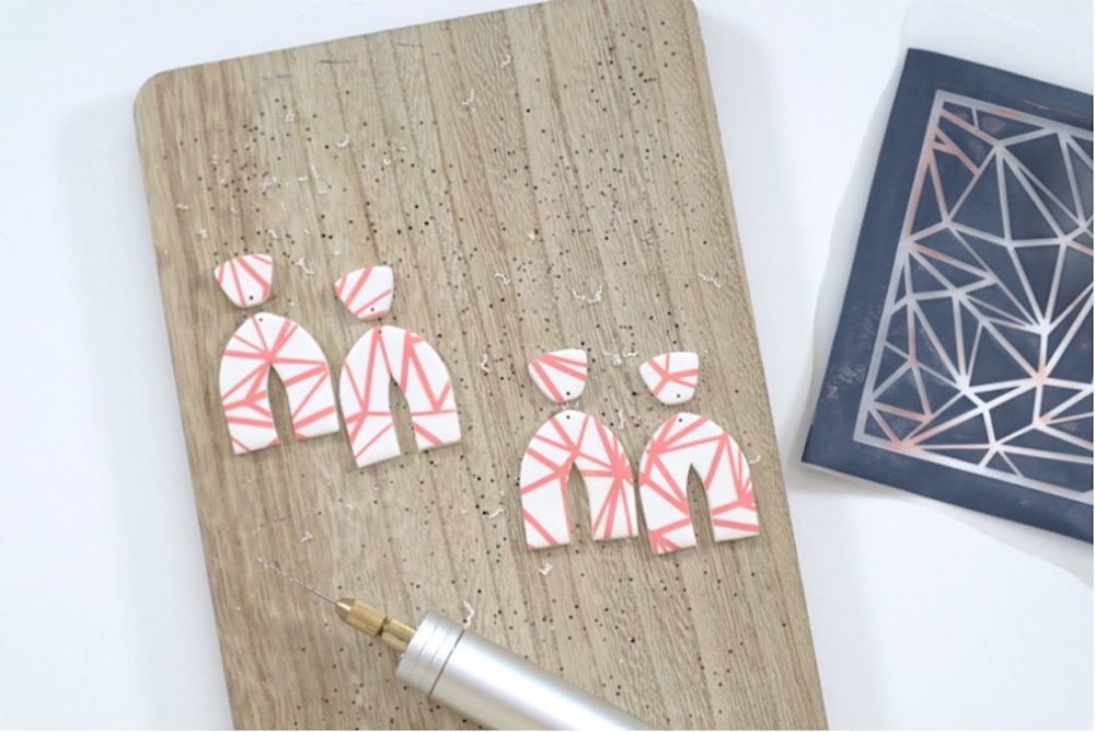 White and pink polymer clay earrings sit on a wood board