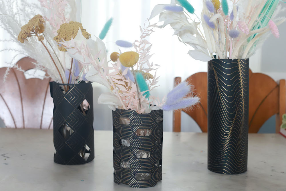 3 floral arrangements become custom wedding centerpieces when wrapped with gold foil cricut cardstock sleeves
