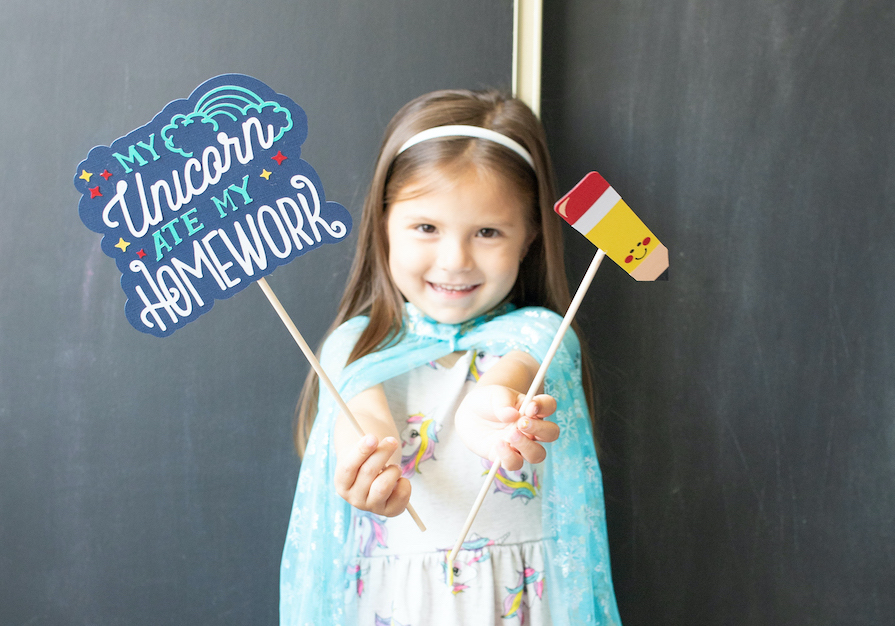 A little girl holds up back-to-school photoshoot props