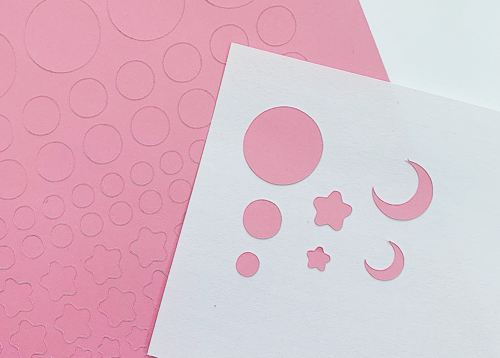 Pink cardstock stickers for bullet journaling are placed on a piece of white card stock 