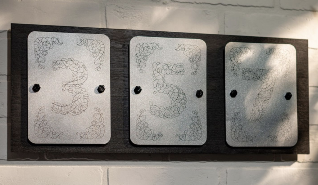 House numbers are etched into metal plating to form metallic decor 