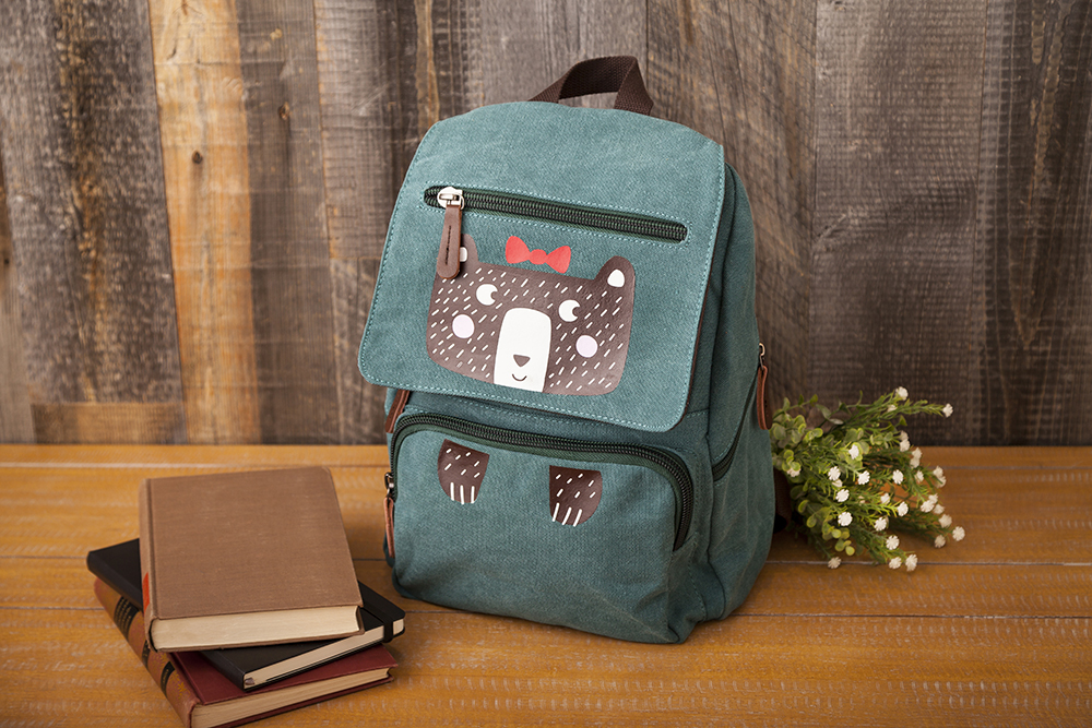 Customized green backpack with bear design on table with books