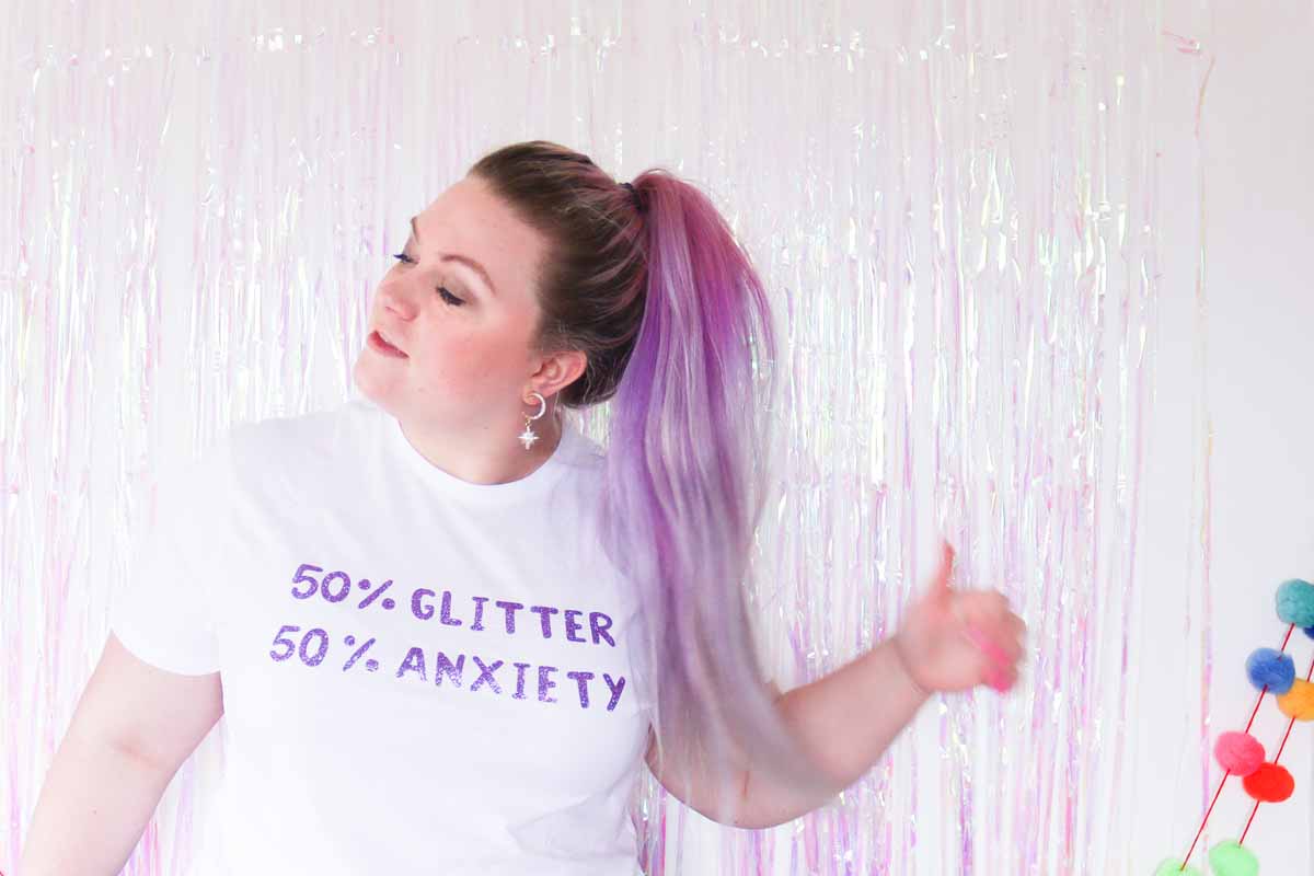 Emma Jewell wearing shirt with design that says "50% Glitter, 50% Anxiety"