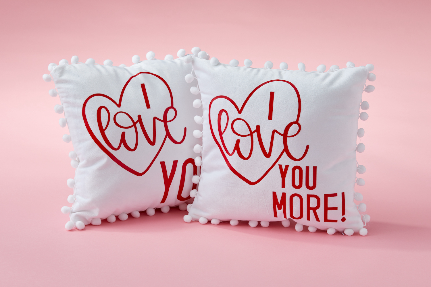 Two throw pillows that say "I Love You More"
