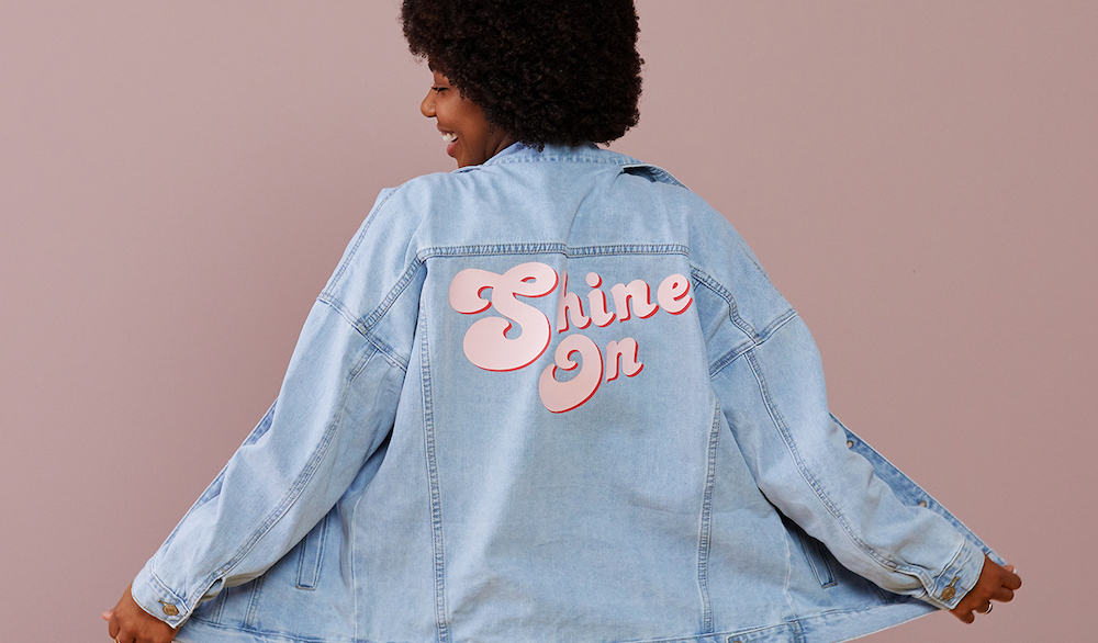 Woman wearing denim jacket with "Shine On" on the back