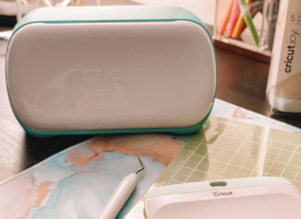 A Cricut Joy machine sits on a blue granite mat and wooden tabletop to be used in a back-to-school classroom organization project 