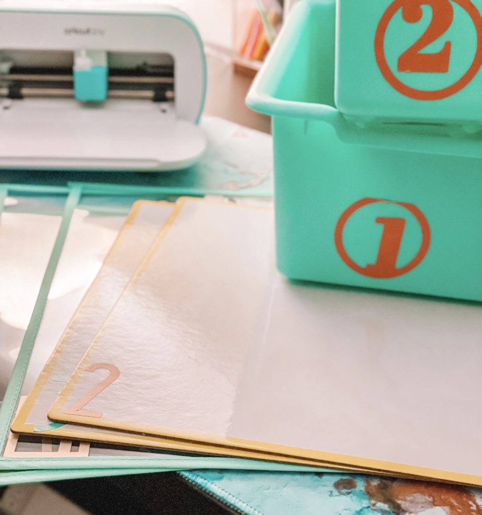 Tote bins and whiteboards are customized with orange vinyl labels as a back-to-school classroom organization project