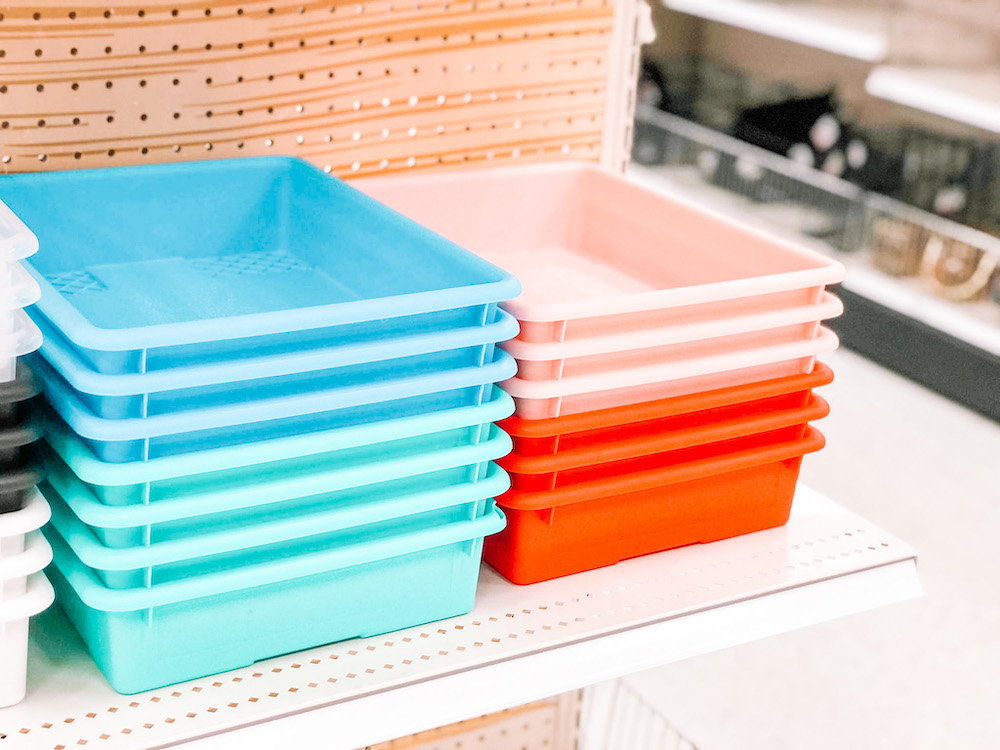 A set of multicolored bins sits on a white store shelf, about to be purchased for use use in a back-to-school organizational project