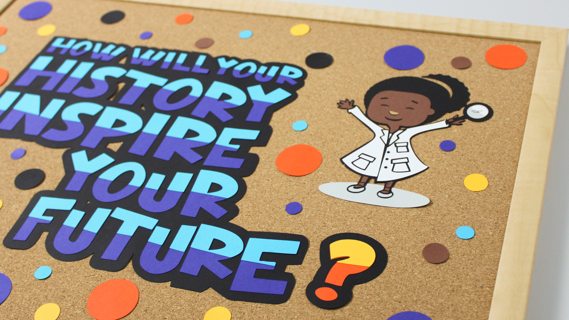 Cork board with paper cut out that says "How will your history inspire your future?"