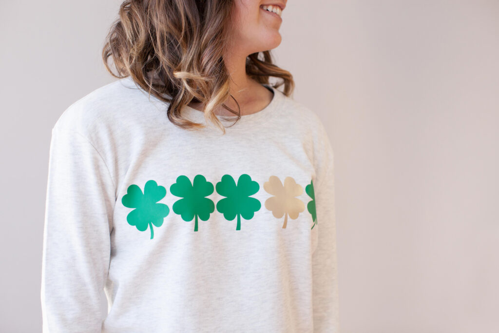 long sleeve white shirt with four green four-leaf clovers and one gold four-leaf clovers made with Cricut