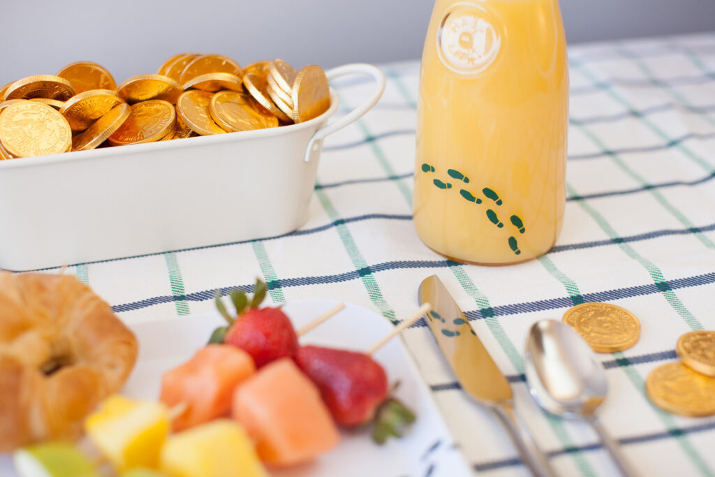 vinyl leprechaun footprints on jar of orange juice on breakfast table for St. Patrick's Day